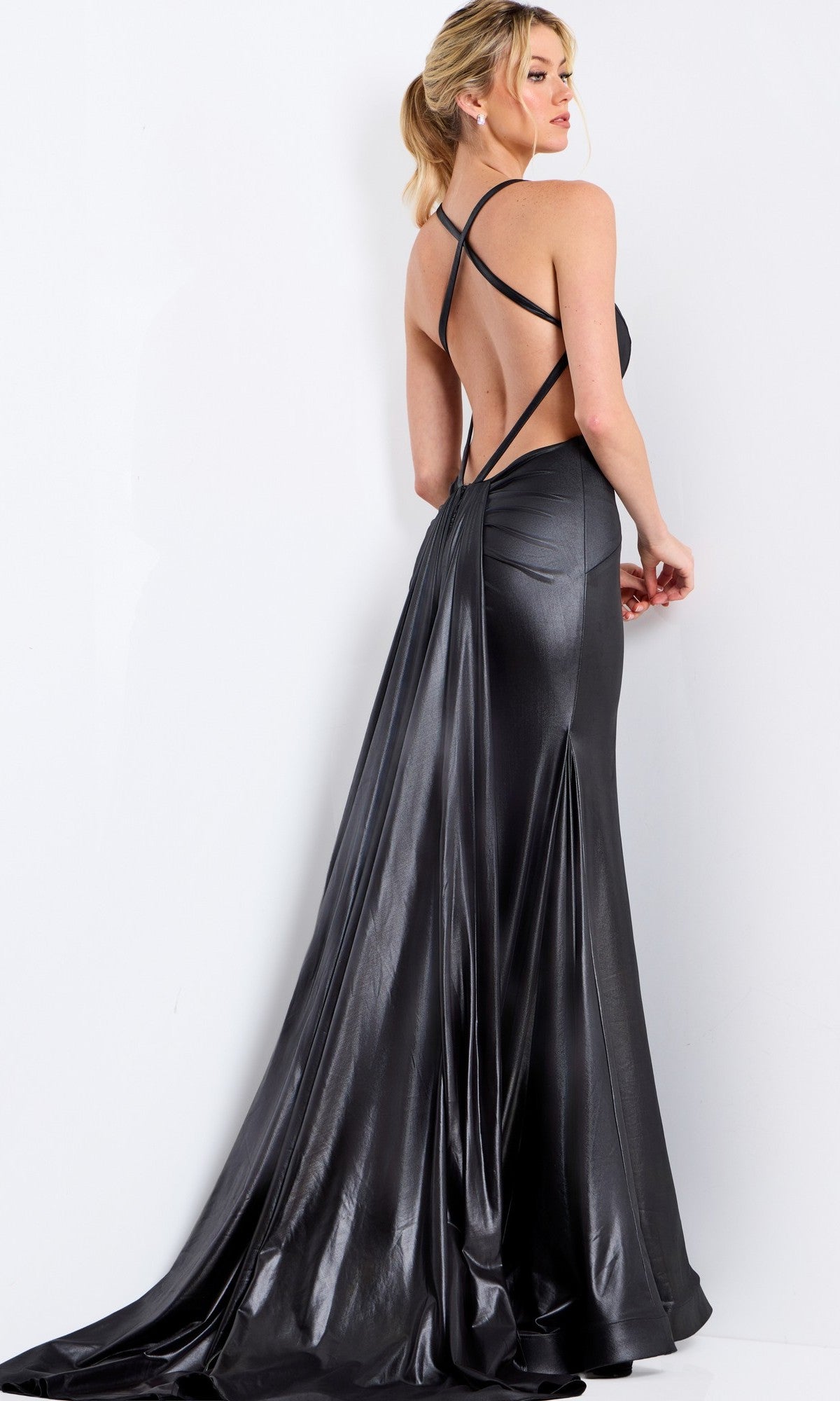 A woman wears the Jovani 48291 long prom dress in shiny dark gray, featuring a strappy open back with crisscross straps, standing against a white background.